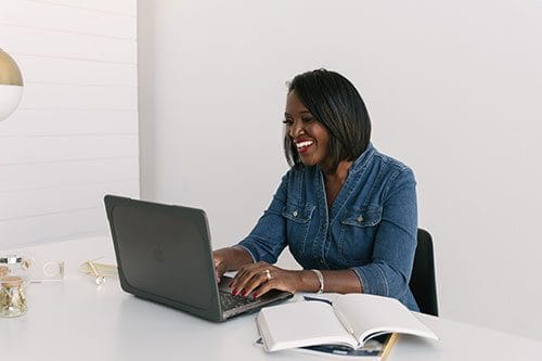 A woman sitting at a table with a laptop.