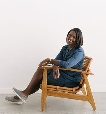 A woman sitting in a wooden chair smiling.