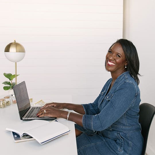 A woman sitting at her desk on top of the laptop.