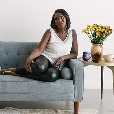 A woman sitting on top of a couch next to a table.