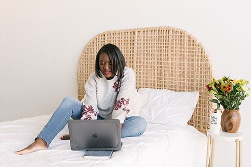 A woman sitting on the bed with her laptop