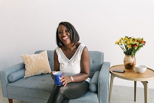 A woman sitting on top of a couch holding a cup.