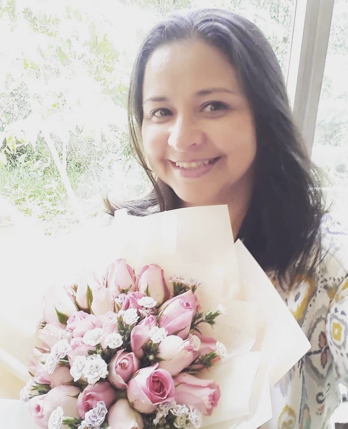 A woman holding flowers in front of her face.