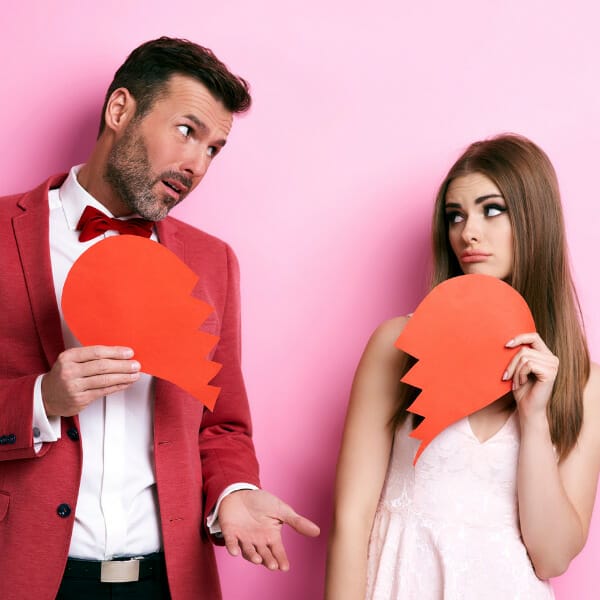 A man and woman holding red paper on pink background.