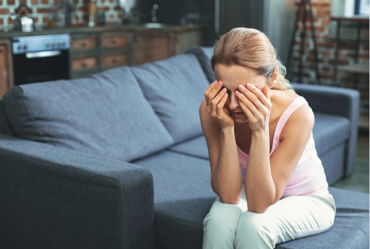 destressed woman on sofa with her hands covering over her face