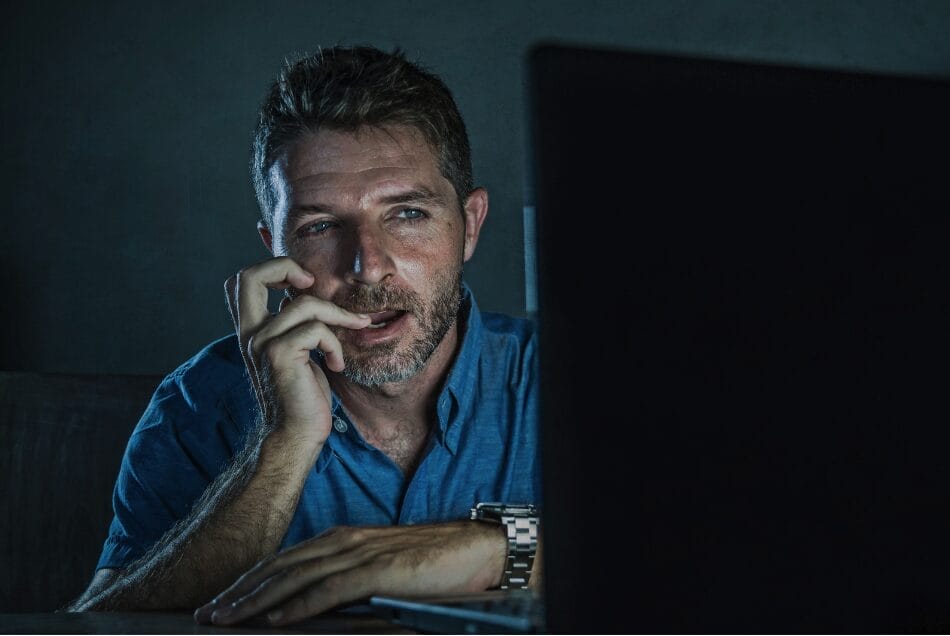 man in dark room looking at computer