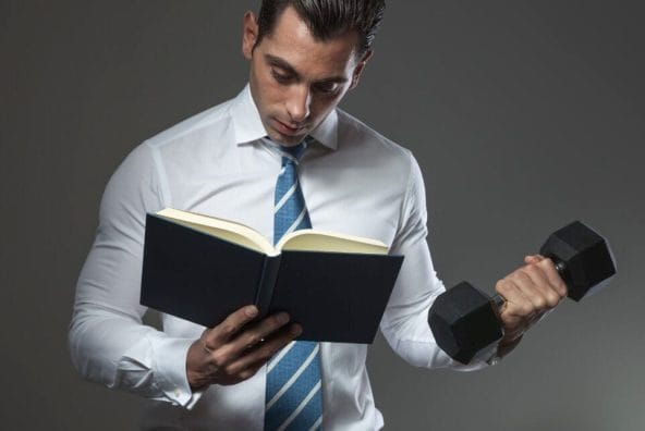 muscular man holding dumbbell and book