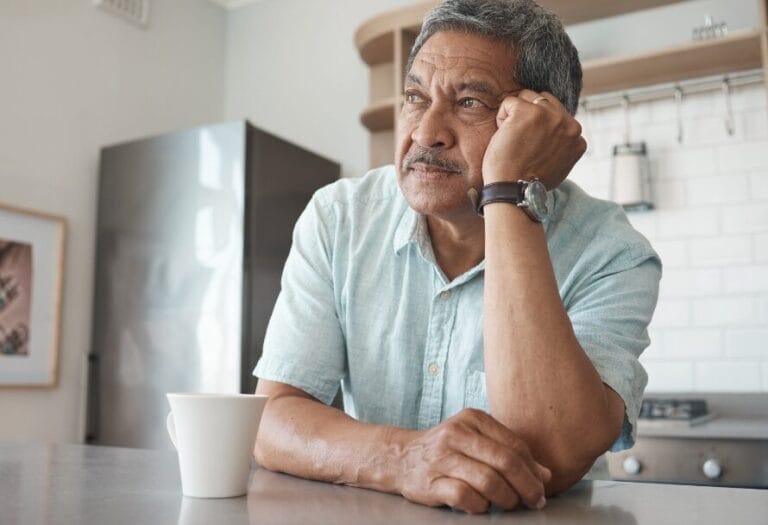 older man alone sitting with mug on table