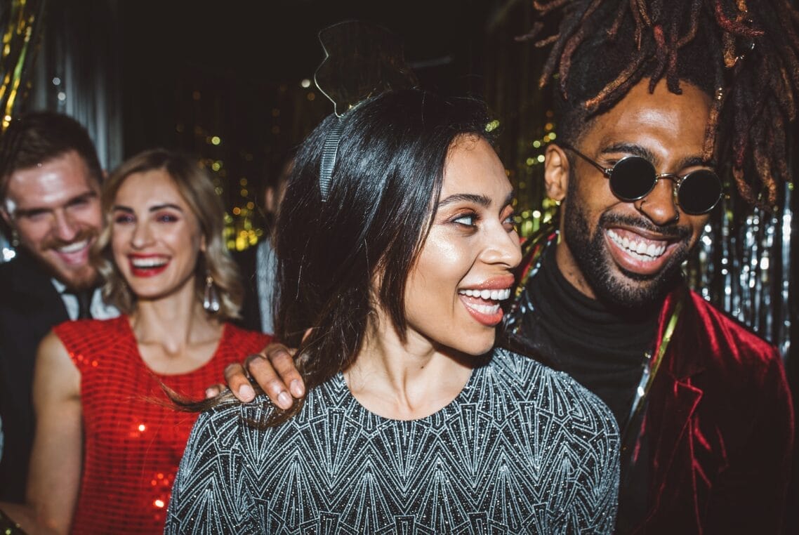 two couples in a party smiling and looking