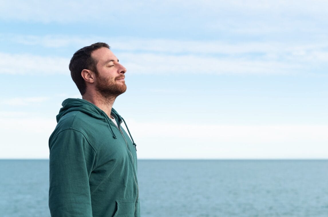 man at beach deeply breathing