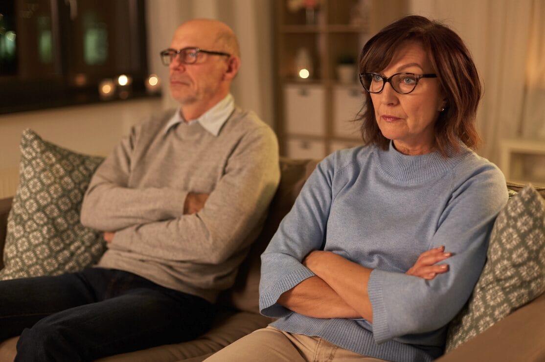 an older couple with their arms crossed and looking upset