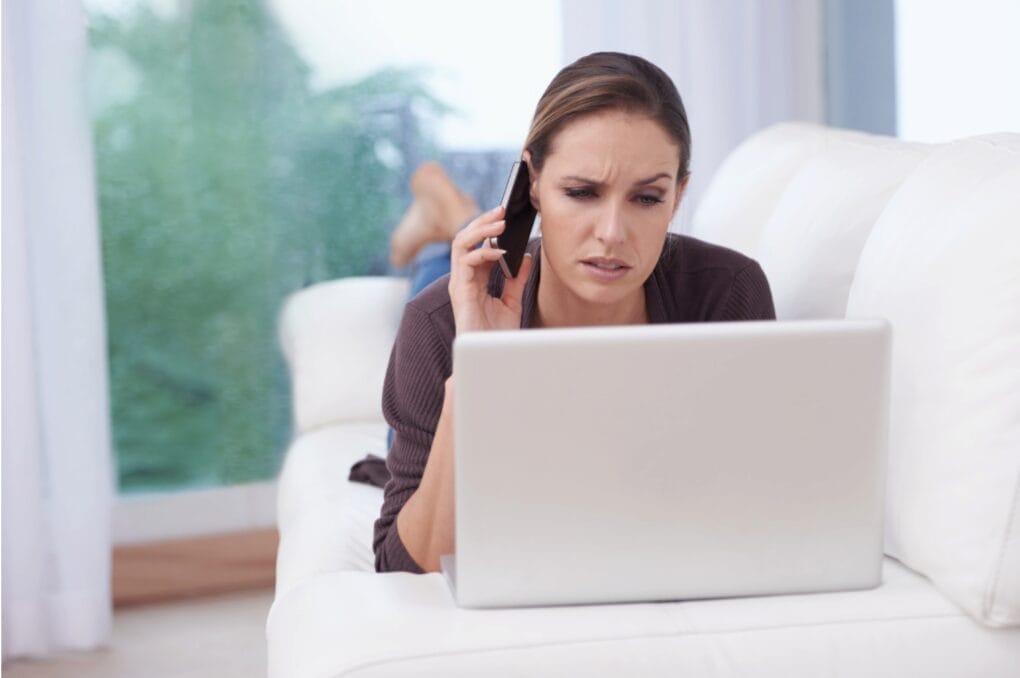 woman on bed looking confused while staring at laptop