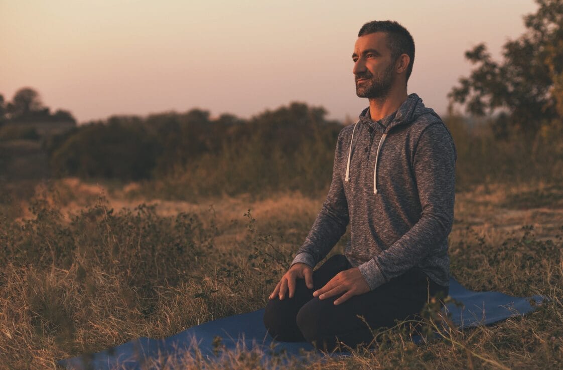 man kneeling looking away outside