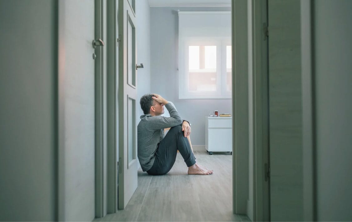 man sitting alone in corner with door open