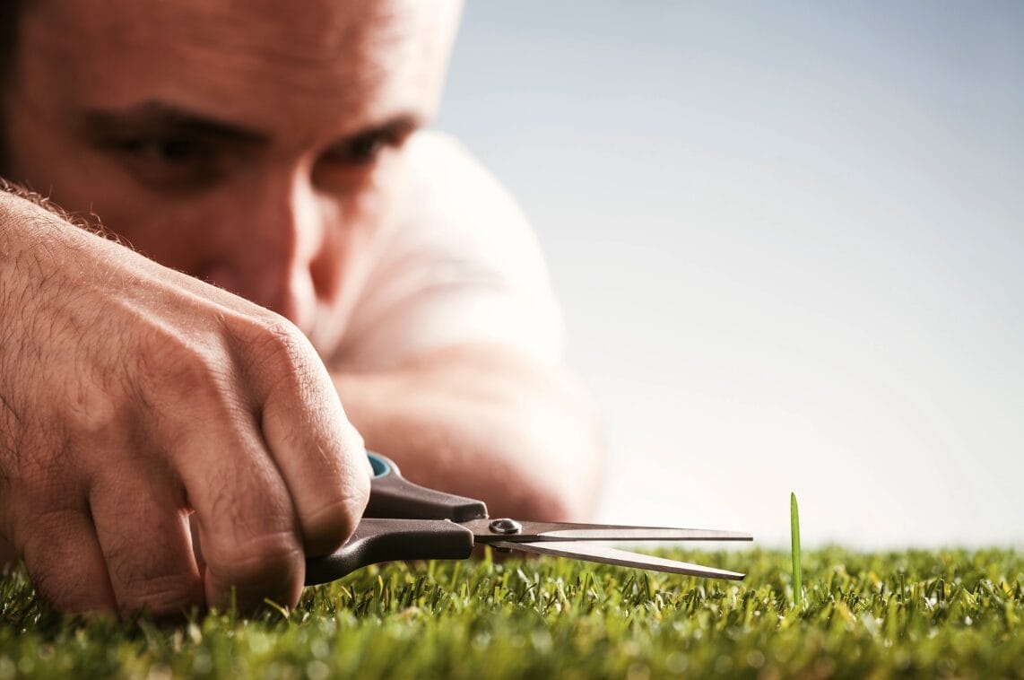 man trying to cut a blade of grass