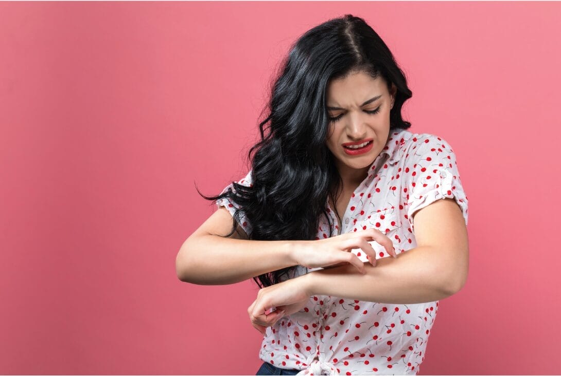 woman in pink background scratching herself