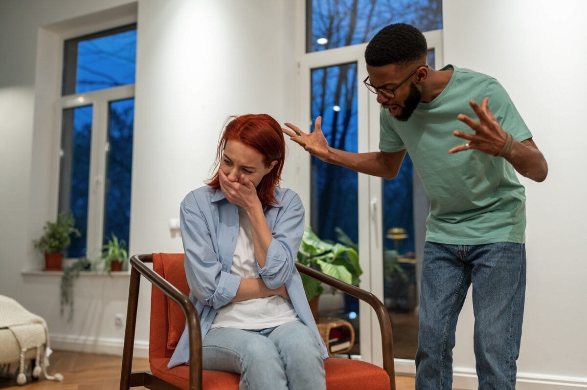 woman sitting in chair being yelled at by man