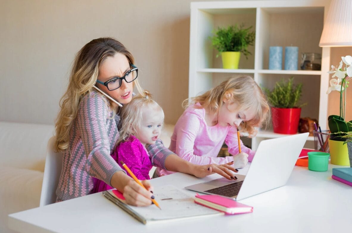 woman trying to talk, look at computer and two with two kids on her lap