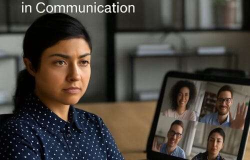 South Asian woman with arms crossed during a Zoom meeting, camera off while others smile onscreen.