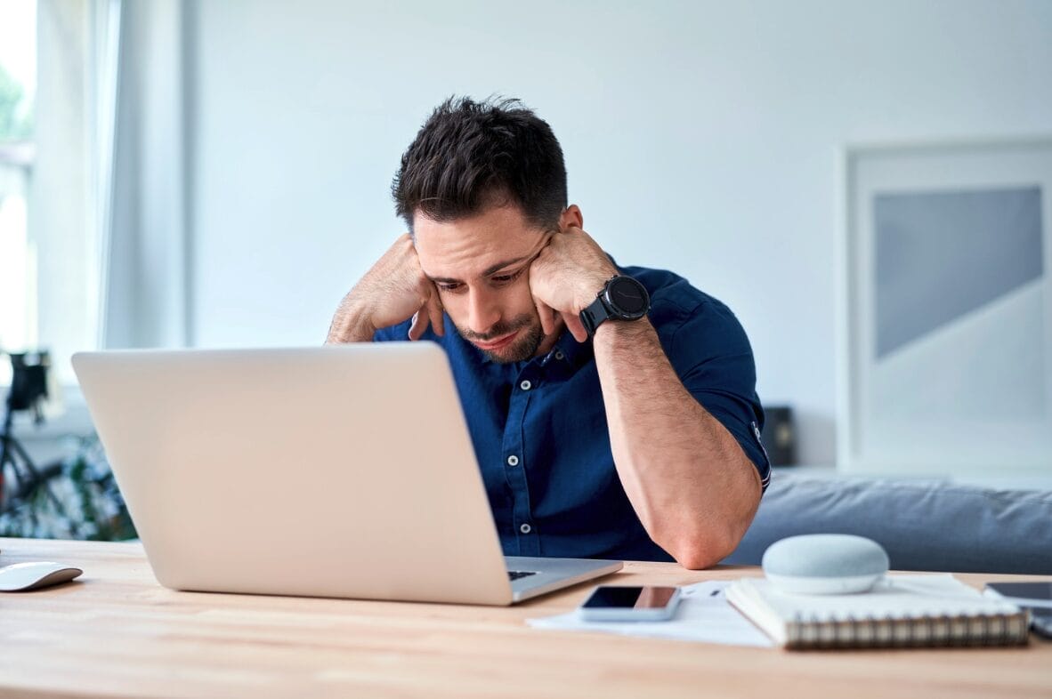 man looking frustrated while looking at laptop