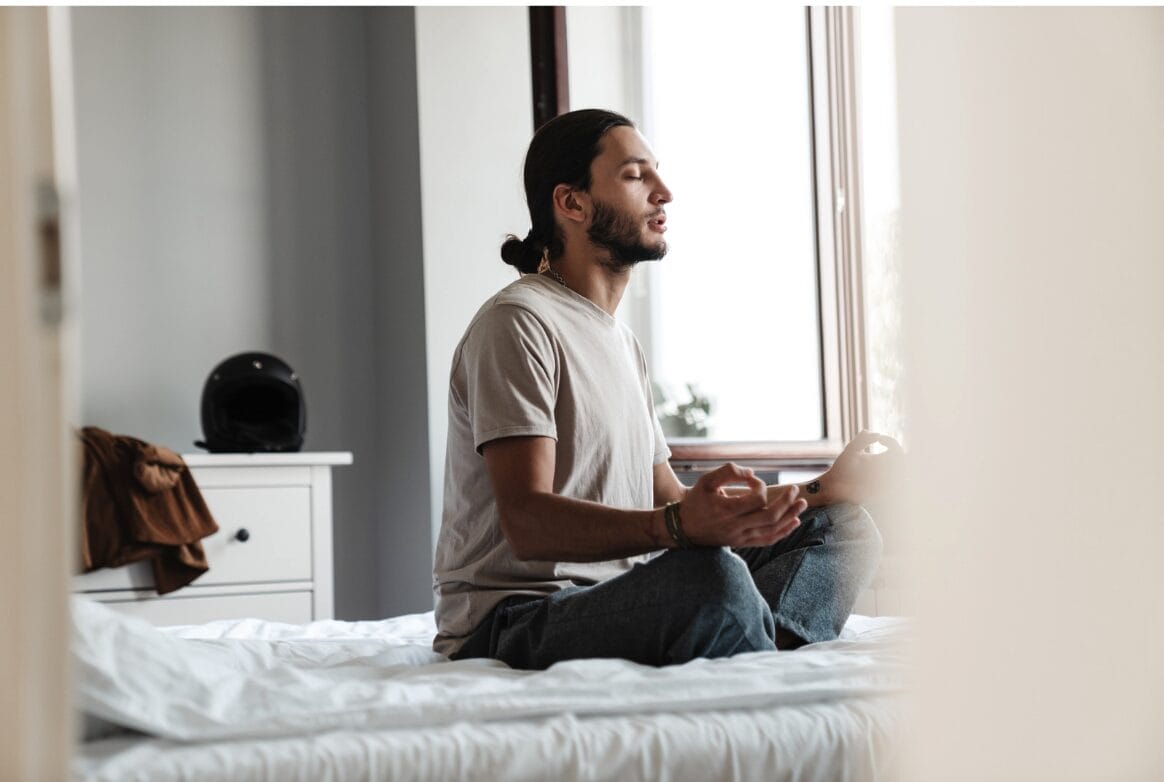 man on bed meditating