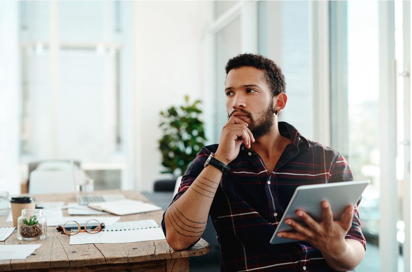 man thinking while holding laptop