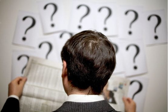 Man looking at newspaper with questions