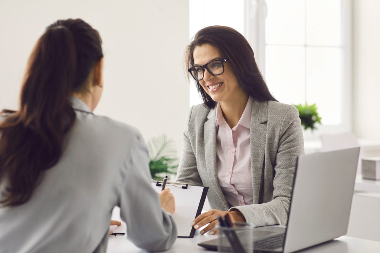 two women at desk, one back facing camera