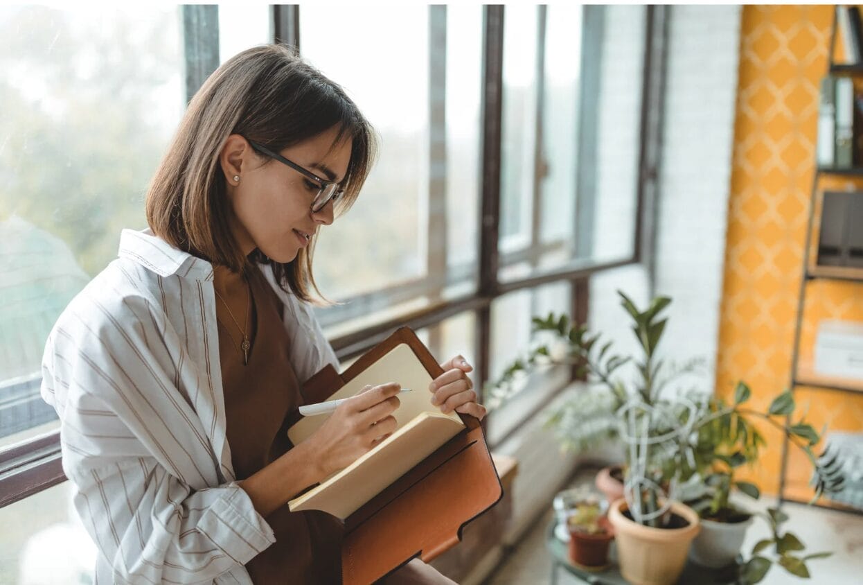 woman journaling next to a window