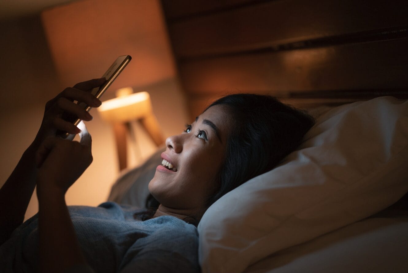 woman looking at phone at night in bed