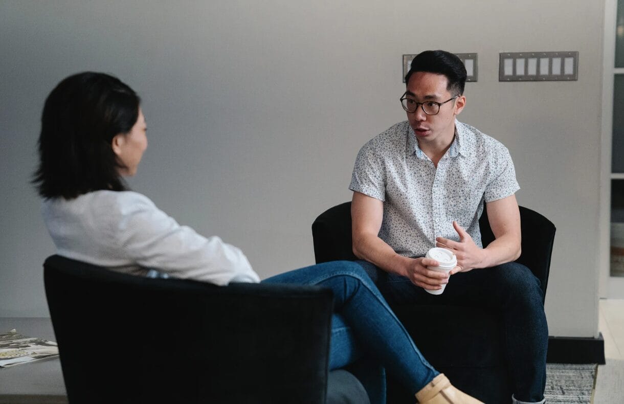 two asian people seated and talking