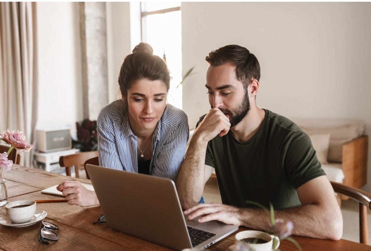 two people leaning aganist laptop at home