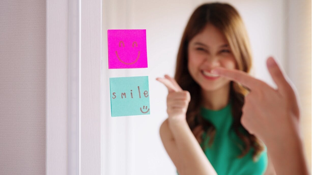 woman looking at sticky note that says smile