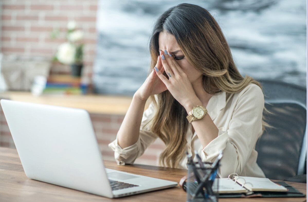 woman with hands on her face in front of laptop