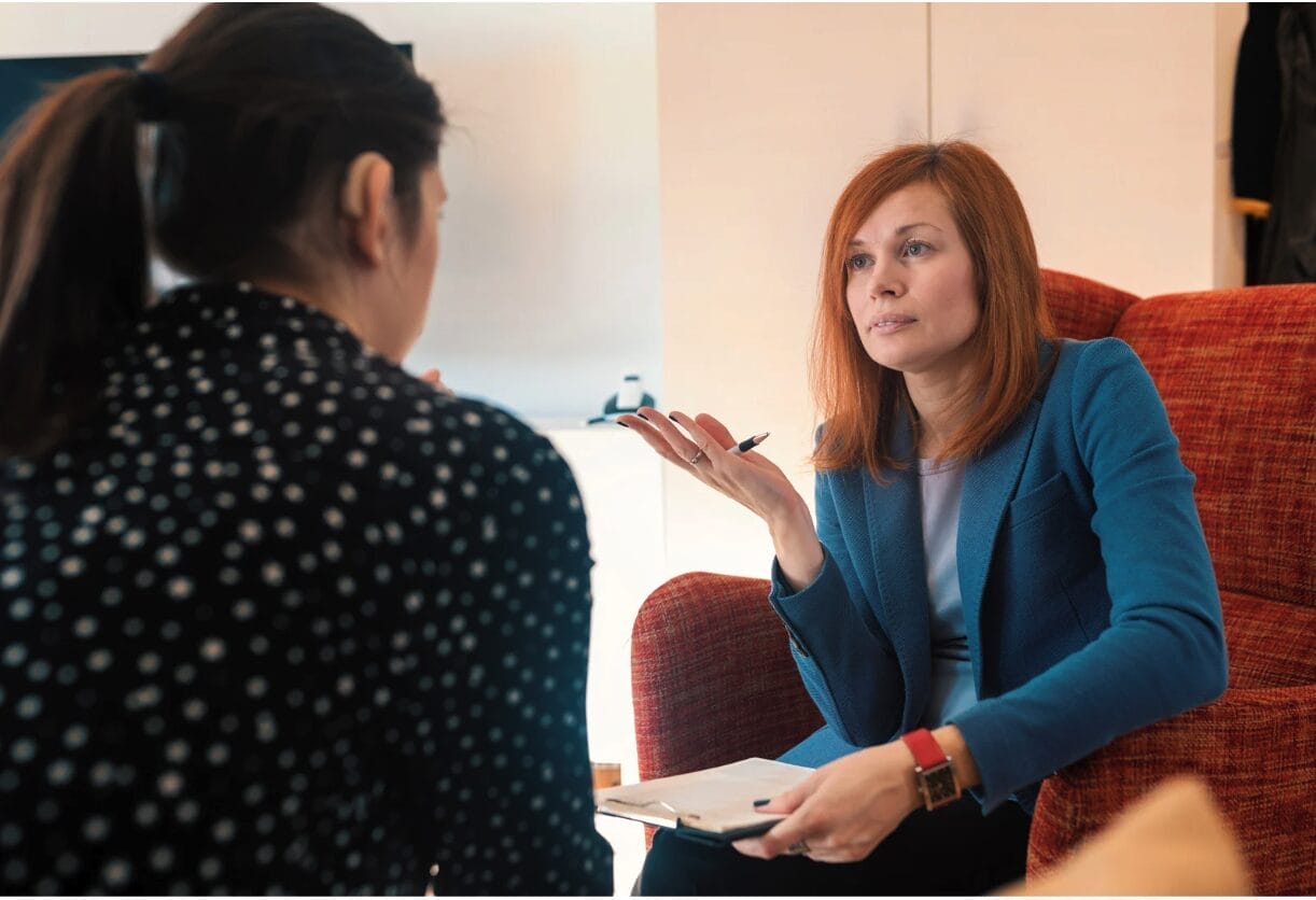 two women talking and one wearing blue blazer