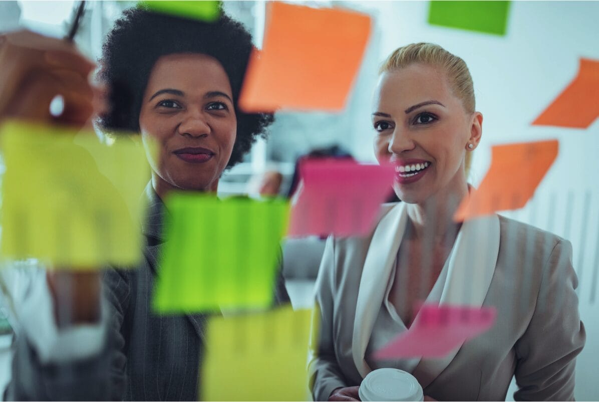 two women at work looking at post it notes