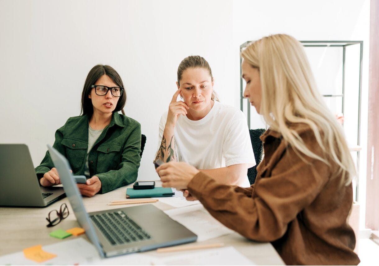 women talking while one looks at laptop