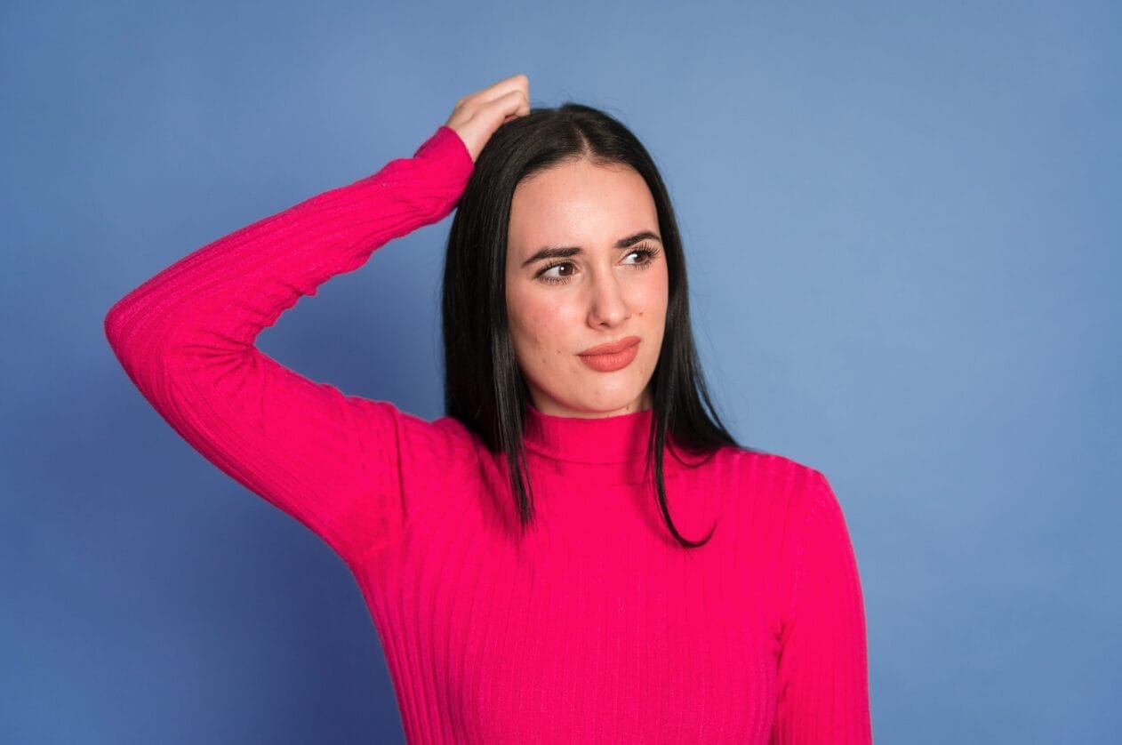 woman wearing pink sweater looking uncertain