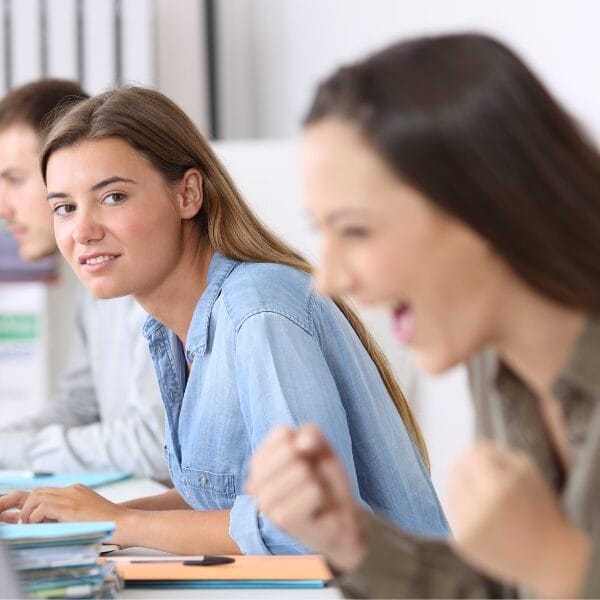 envious woman stares at another woman while at desk