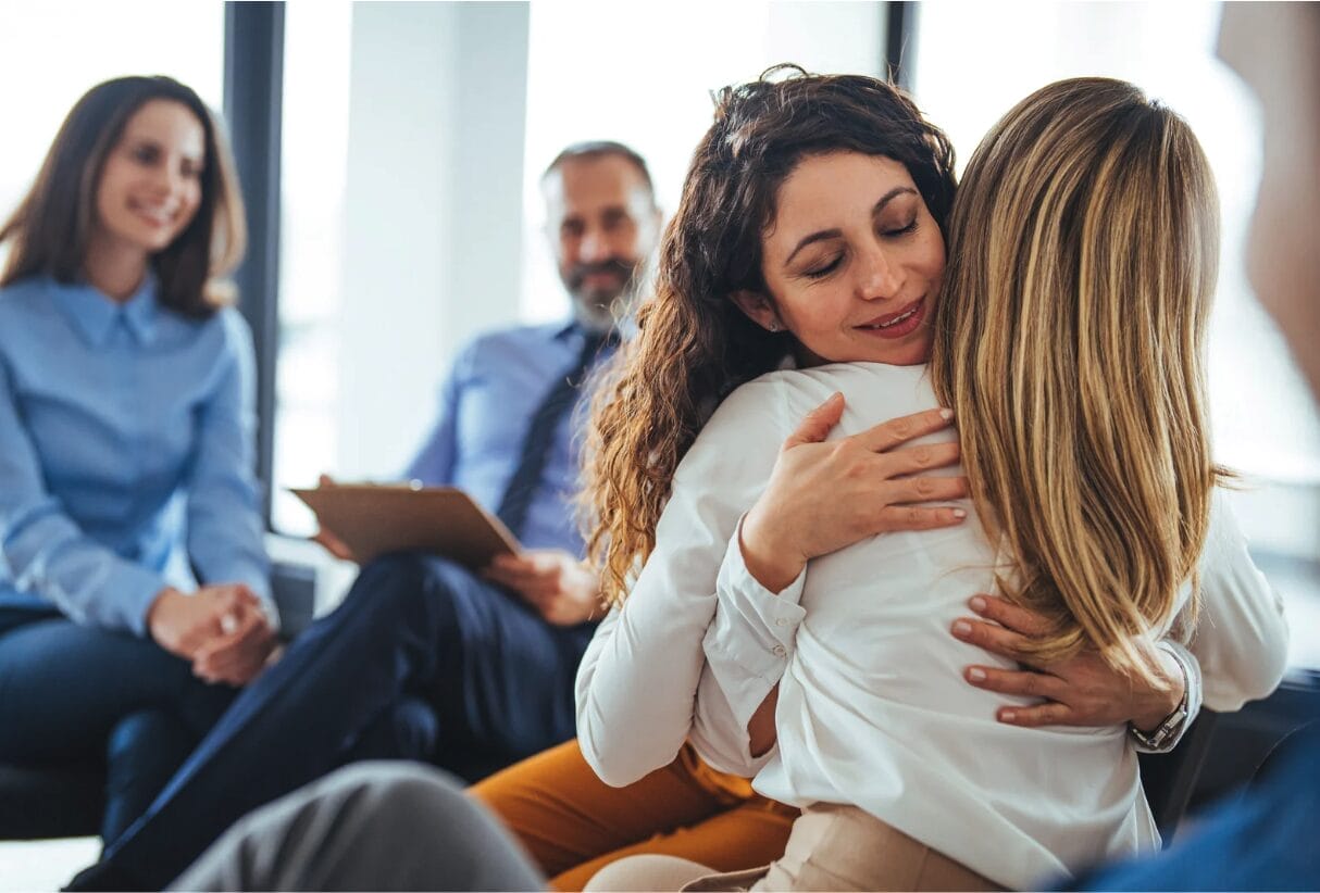 two women hugging in a business meeting