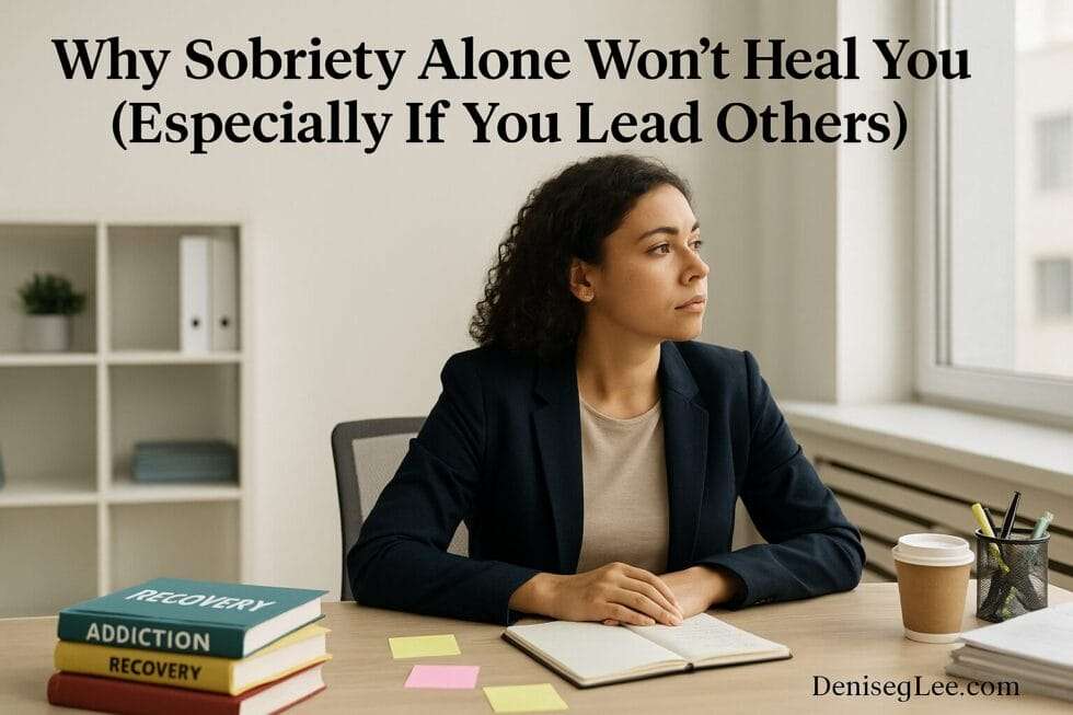 Woman in a professional setting staring out the window with recovery books and notes on the desk, reflecting on sobriety and leadership struggles
