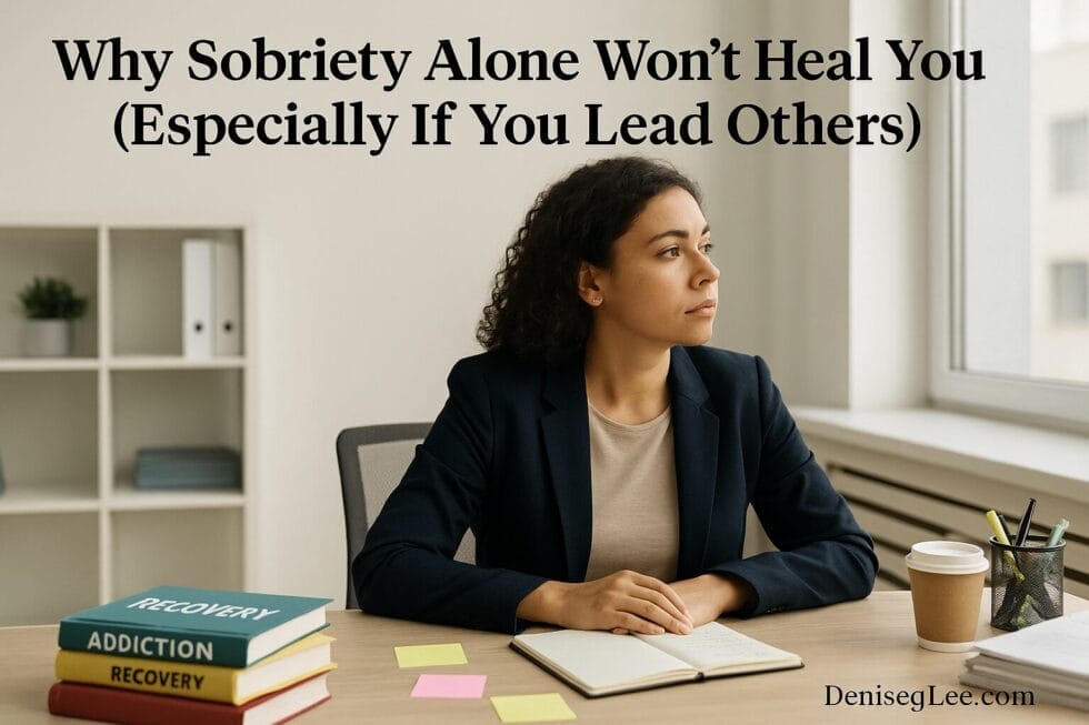 Woman in a professional setting staring out the window with recovery books and notes on the desk, reflecting on sobriety and leadership struggles