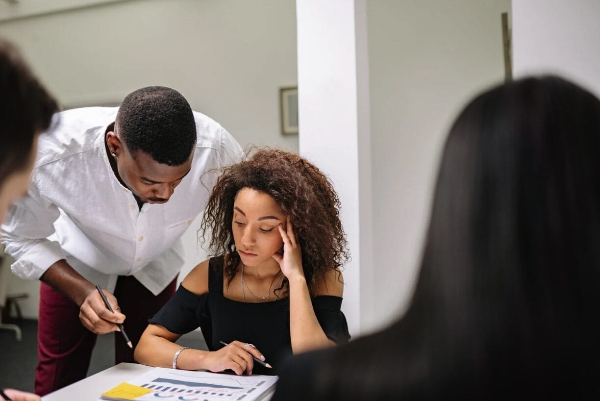 women leaning at papers looking uncomfortable