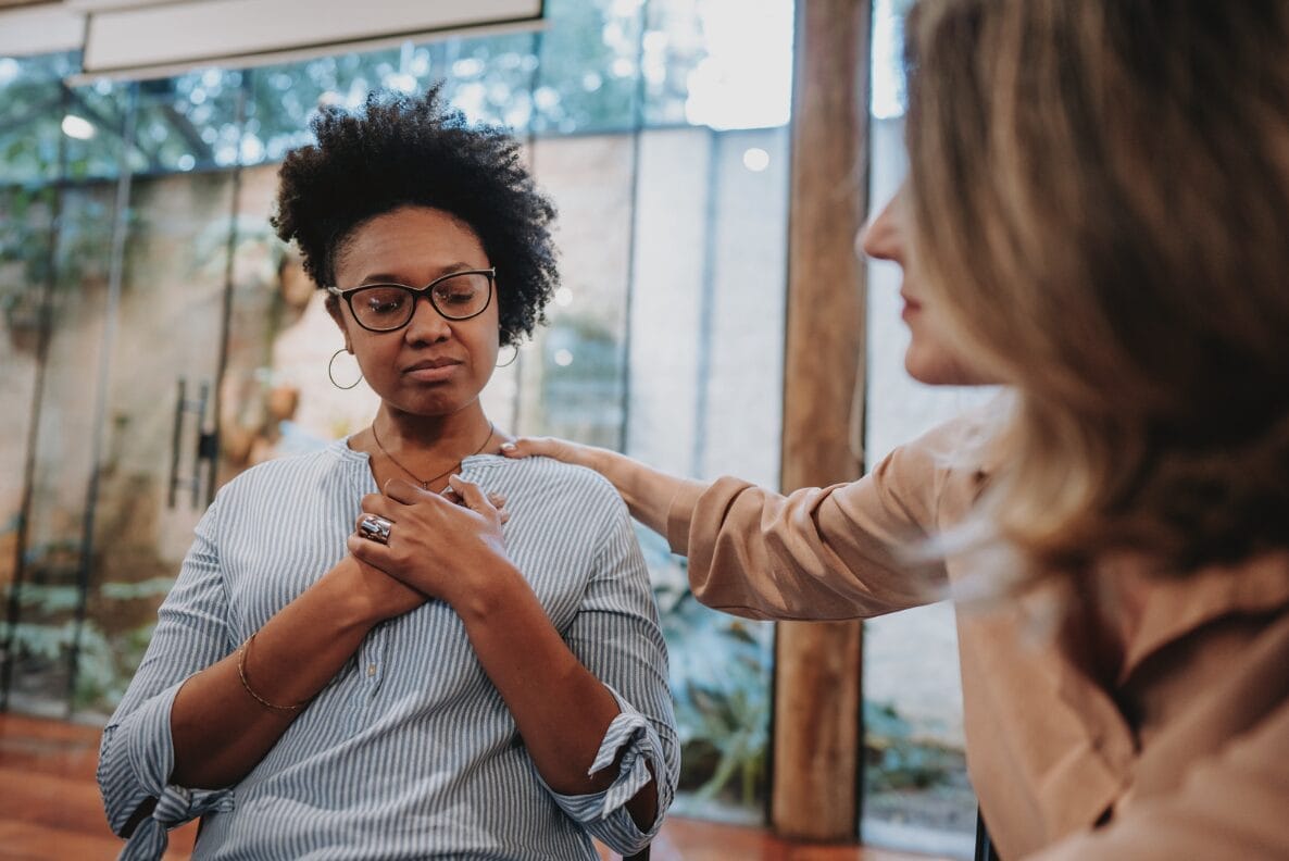 woman being comforted by another holding their hand