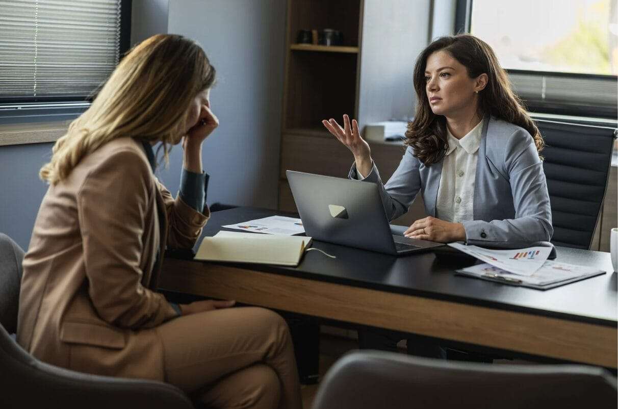 woman being scolded by another woman while at desk