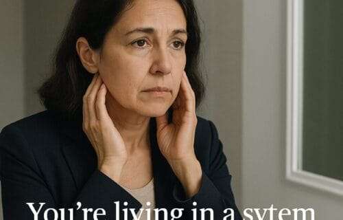 Woman in her 40s or 50s looking thoughtfully into a mirror, representing the emotional tension of aging and professional visibility